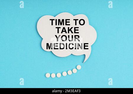 Medicine and health concept. On a blue table are pills and a white plate with the inscription - Time to take your medicine Stock Photo