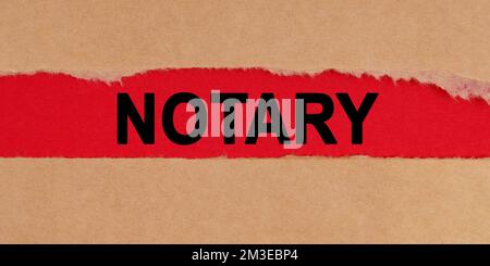 Law concept. Among the torn sheets of paper on a red background, the inscription - NOTARY Stock Photo