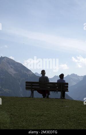 In the mountains, pensioners relax on a bench Stock Photo