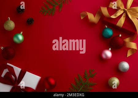 christmas gifts, ornaments and pine cone with red background with copy space in the middle area Stock Photo