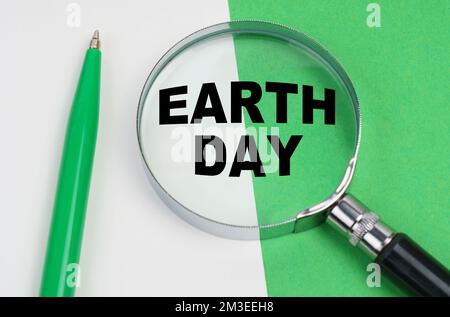 Ecological concept. On a white-green background lies a pen and a magnifying glass, inside which is the inscription - earth day Stock Photo