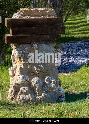 Blank signpost in a poplar forest. Wooden sign on stone milestone. Sunny day Stock Photo