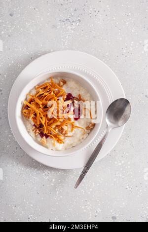 rice pudding with Norwegian brunost traditional brown cheese and raspberry jam Stock Photo