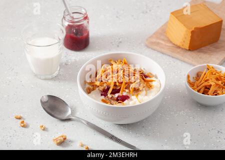 rice pudding with Norwegian brunost traditional brown cheese and raspberry jam Stock Photo