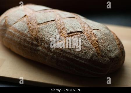 freshly baked bread on dark gray kitchen table and wooden board, close-up, angle view Stock Photo