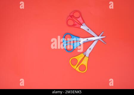 three brightly colored pairs of  craft scissors isolated on an orange background Stock Photo