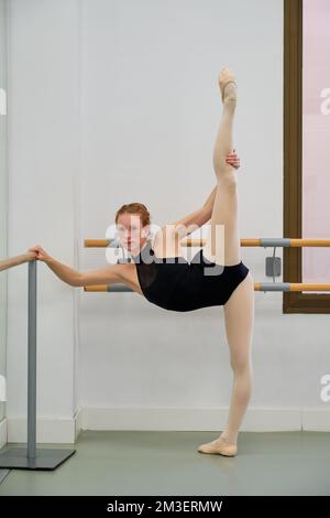 Young ballerina practicing ballet pose in a ballet school. Stock Photo
