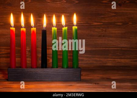 Kwanzaa festival concept with seven candles red, black and green in candlestick on wooden background, Stock Photo