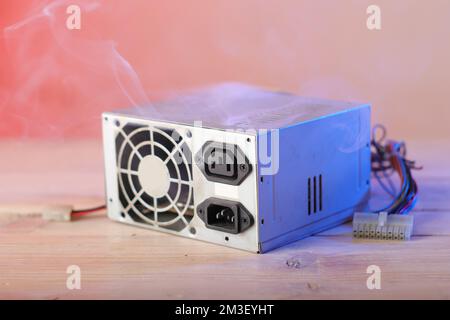 old computer power supply burning on the table and pink background ...