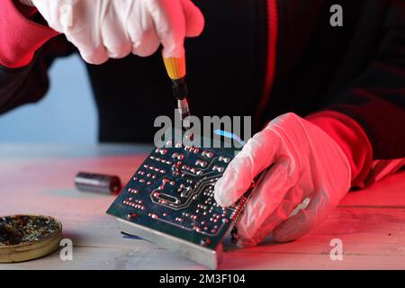 unscrewing the screws from the printed circuit board by a person Stock Photo