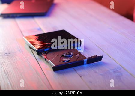 laptop optical drive with open tray on table and colored background Stock Photo