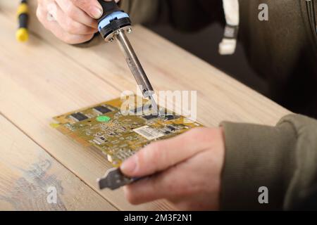 person soldering computer graphics card on table and gray background Stock Photo