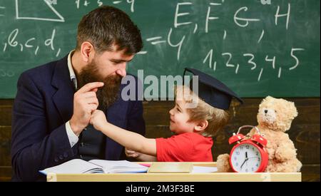 Father with beard, teacher teaches son, little boy, while child beating him. Kid cheerful boxing, beating dad. Playful child concept. Teacher and Stock Photo