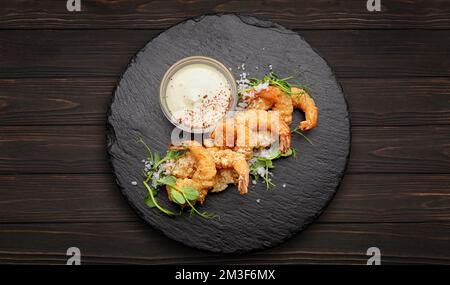 Fried shrimps in batter with sauce, on black slate, on a dark wooden background Stock Photo