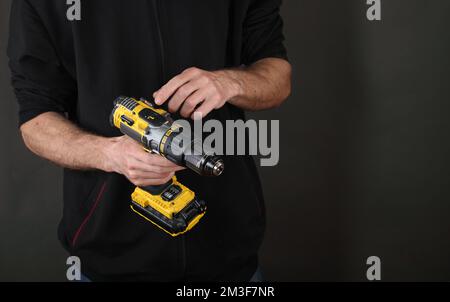 person holding a screwdriver in hands on a gray background Stock Photo