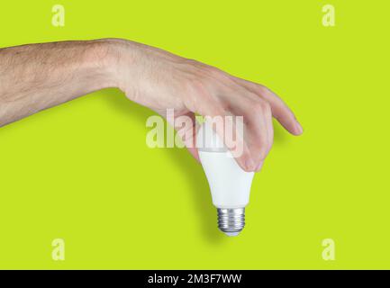 hand holding led light bulb on green background Stock Photo