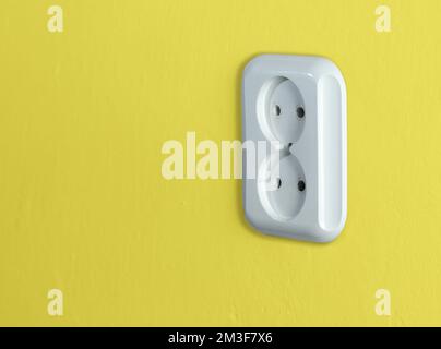 white two-port socket on the yellow wall Stock Photo