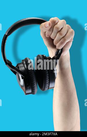 black wireless headphones in hand on a blue background Stock Photo