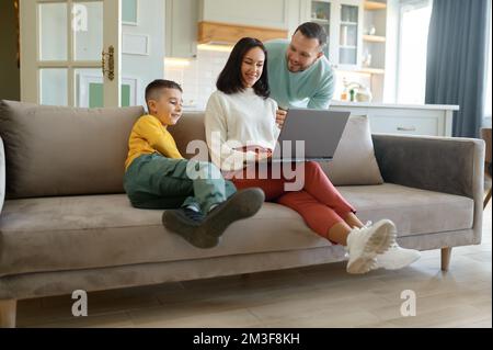 Happy family at home with mother working on laptop Stock Photo