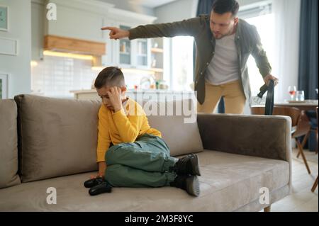 Father with leather belt shouting on son playing computer video games Stock Photo