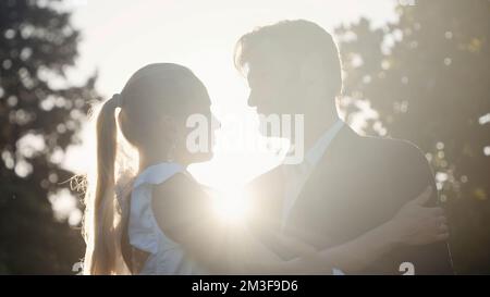 Posing of the newlyweds. Action.A beautiful young couple with a blonde girl in big earrings and her husband with a beard who are sitting and hugging o Stock Photo