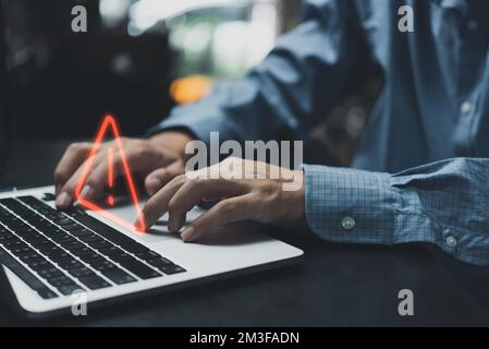 Businessman programmer, developer using laptop computer with triangle caution warning sign for notification error and maintenance concept. Stock Photo