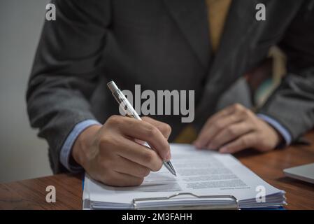 businessman signs documents with a pen making the signature on desk. Stock Photo
