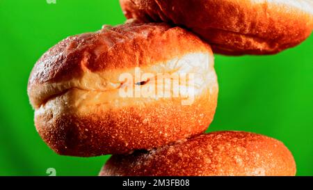 Lush sweet buns on a green and pink background. Stock clip.Sweet donuts that are poured with white sugar cream and filmed in close-up. High quality 4k Stock Photo