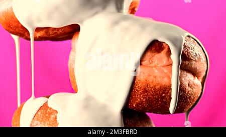 Lush sweet buns on a green and pink background. Stock clip.Sweet donuts that are poured with white sugar cream and filmed in close-up. High quality 4k Stock Photo