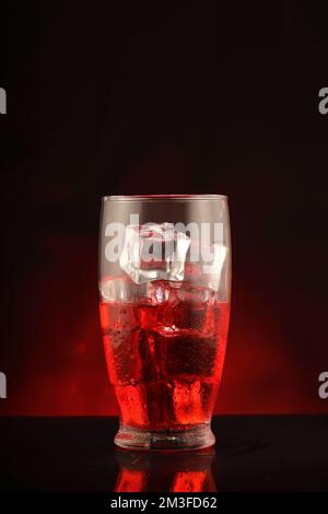 glass with alcohol and ice cubes on black background and red gradient Stock Photo