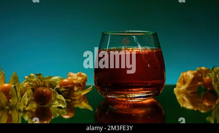 A bright illuminated still life. Stock clip . A beautiful roomy mug in which brandy is poured and small oranges and tangerines lie next to it. High qu Stock Photo