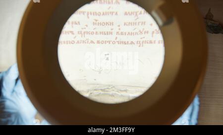 Reading prayers. Stock footage.An old prayer book with Old Slavic letters and a white letter that is viewed under a huge magnifying glass. High qualit Stock Photo