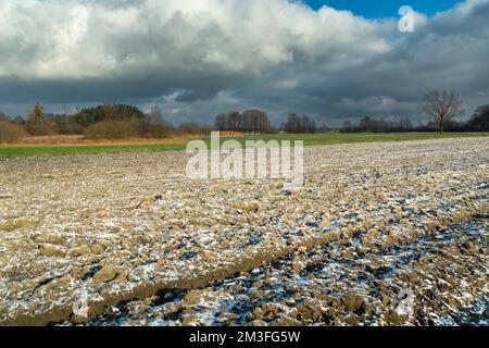 Small snow on a plowed field and cloudy sky, eastern Poland Stock Photo