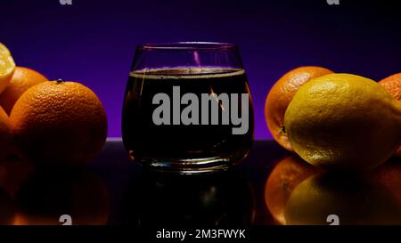 Soda bubbles in a glass against a dark wall changing colors. Stock clip. Soft drink in transparent glass with orange fruits Stock Photo