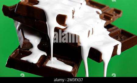 Close up of chocolate bars with draining white glaze isolated on chroma key green wall background. Stock clip. Black chocolate and white glaze Stock Photo