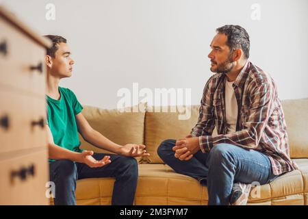 Father and son are talking at home. Son is having issues and father is consoling him. Stock Photo