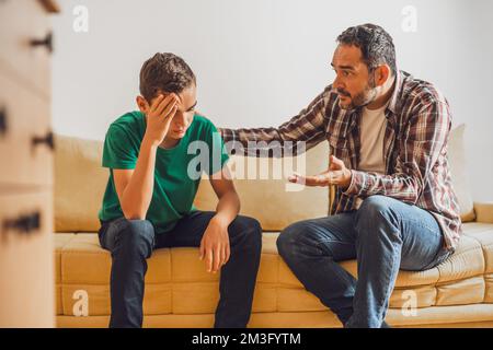 Father and son are talking at home. Son is having issues and father is consoling him. Stock Photo