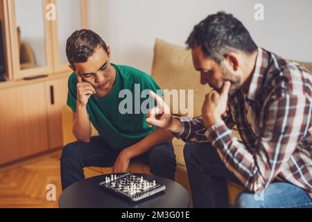 Father and son are playing chess at home. Stock Photo