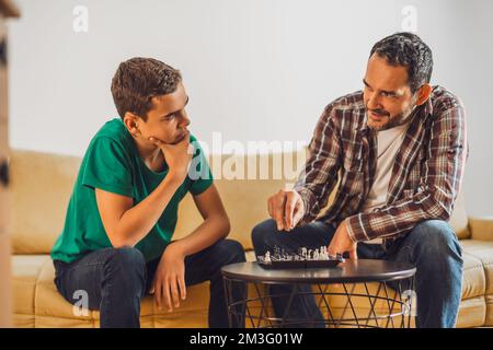 Father and son are playing chess at home. Stock Photo