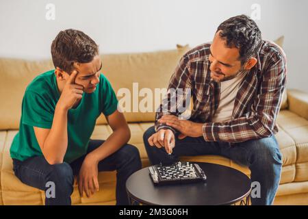Father and son are playing chess at home. Stock Photo