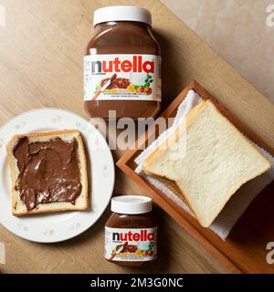 Nutella with large and small bottles and some white bread neatly arranged on the dining table Stock Photo