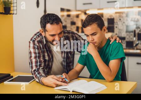Father is helping his son with learning. They are doing homework together. Stock Photo