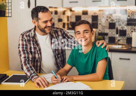 Father is helping his son with learning. They are doing homework together. Stock Photo