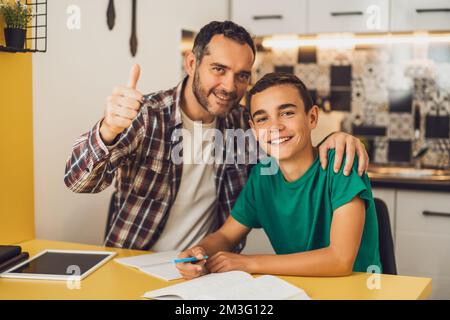 Father is helping his son with learning. They are doing homework together. Stock Photo