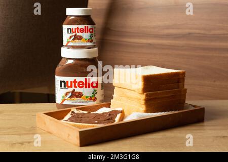 Nutella with large and small bottles and some white bread neatly arranged on the dining table Stock Photo