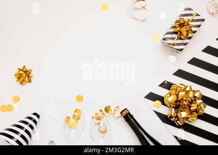 Christmas party composition. Gifts, hats, black and gold decorations on white background. Flat lay, copy space Stock Photo