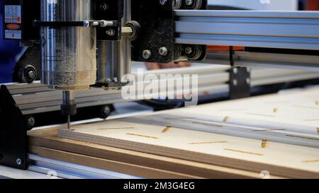 Industrial robot using automatic screwdriver on wooden product. Media. industrial machine at work at the construction site or factory Stock Photo
