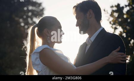 Posing of the newlyweds. Action.A beautiful young couple with a blonde girl in big earrings and her husband with a beard who are sitting and hugging o Stock Photo