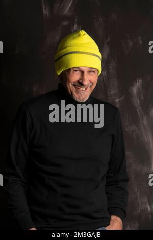 Older man with yellow winter cap laughs Stock Photo