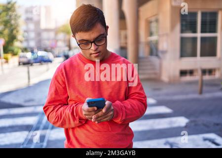 Down syndrome man using smartphone with serious expression at street Stock Photo